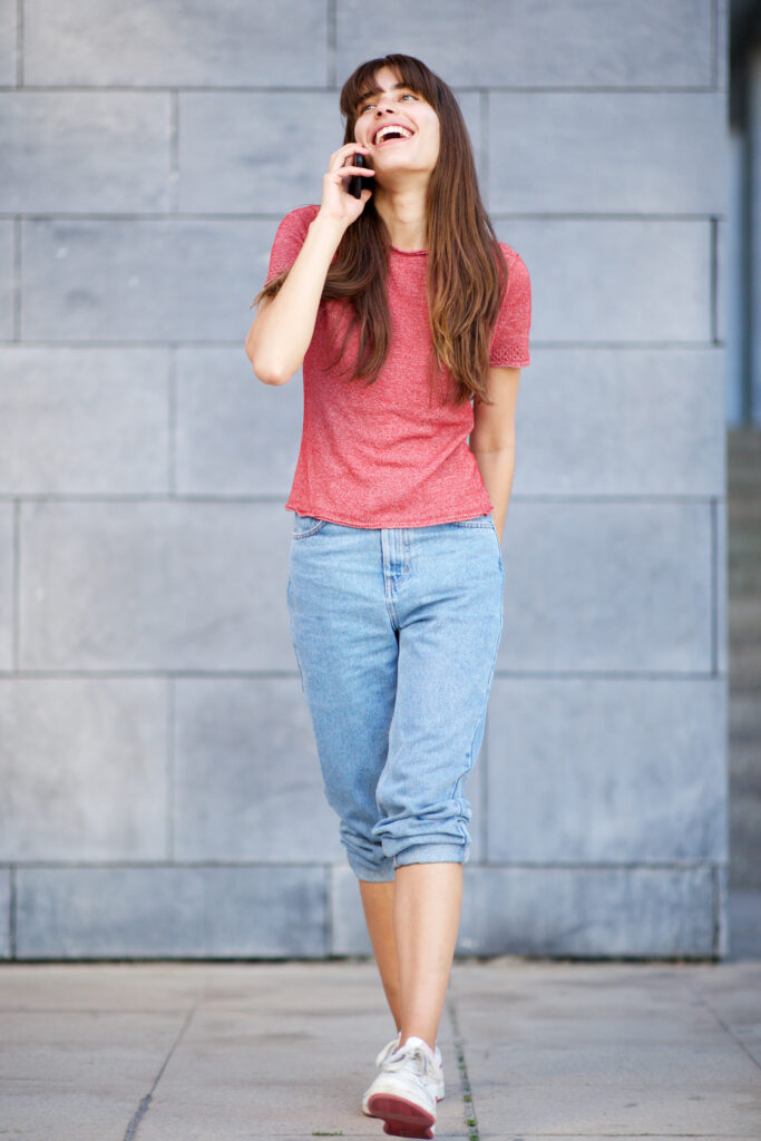 Full body portrait smiling young woman talking with cellphone