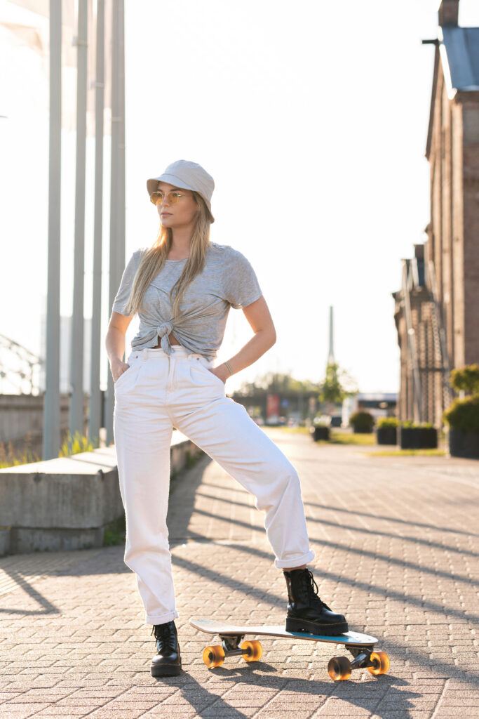 Portrait of young stylish girl wearing panama hat with a longboard in a city